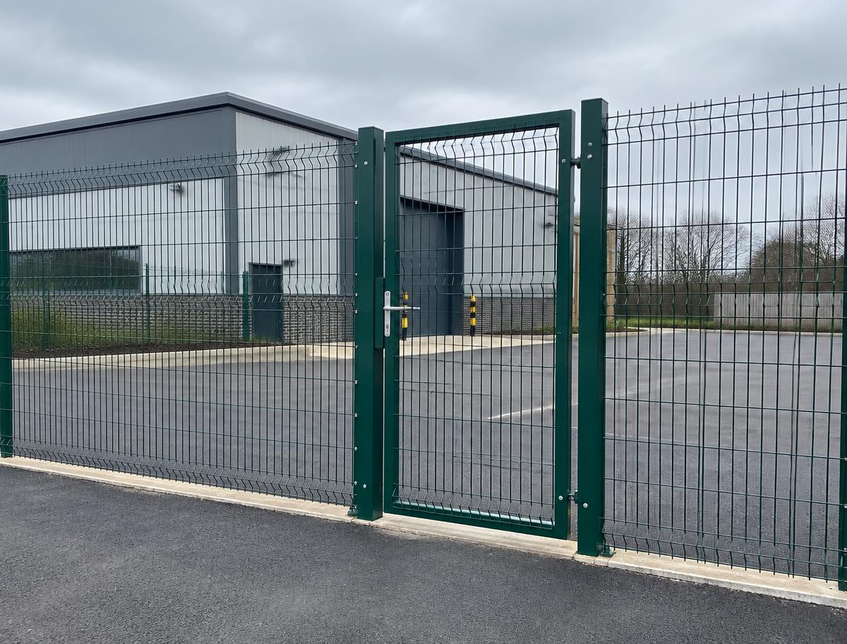 Illustration of green mesh security fencing and pedestrian gate around a commercial yard